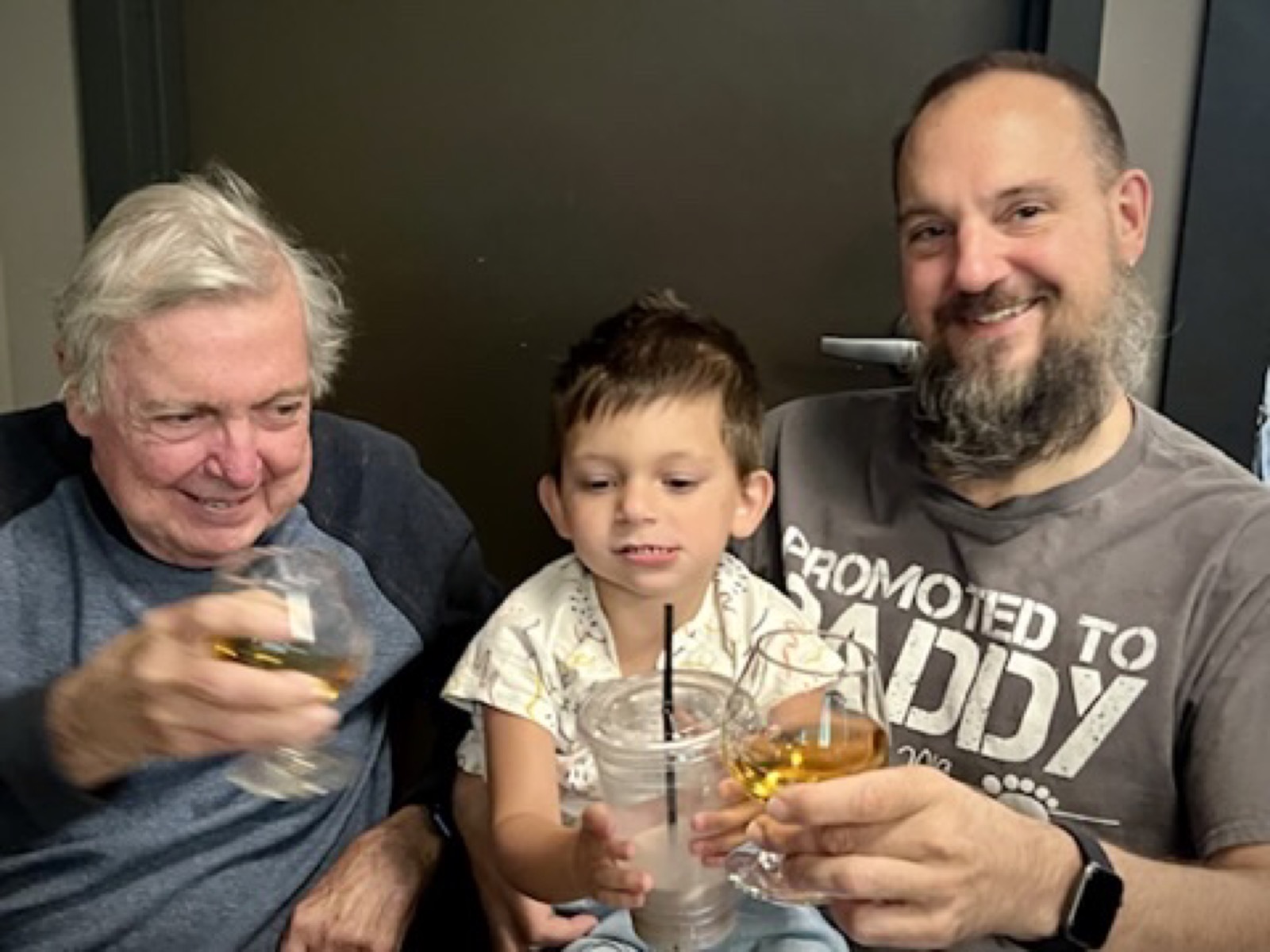 Dad, Jeff, and Khoren raising drinks at a table on Father's Day 2022