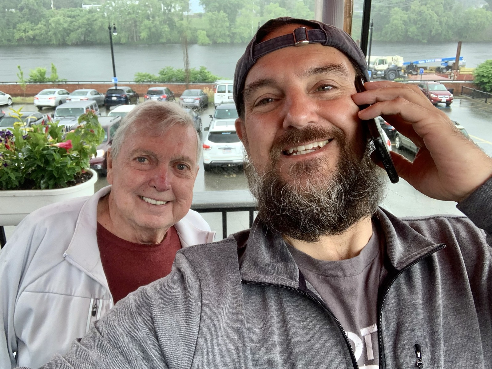 Jeff and Dad smiling in a rainy riverside selfie on Father's Day 2023